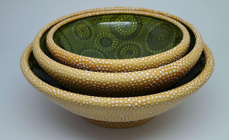 Set of large nesting bowls with rolled rims, glazed on inside, dotted on outside