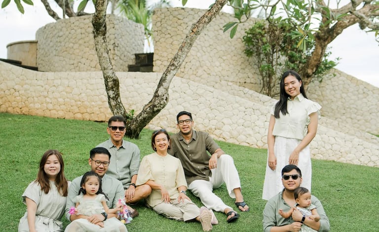 Large family enjoying time together in a tropical garden during a Bali family photography session.