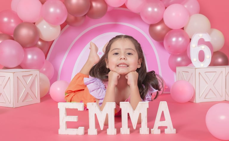 a little girl is posing for a photo in front of a pink arch arch arch