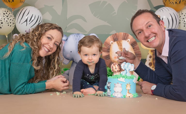 a man and woman with a baby in front of a cake