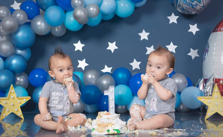 two babies are sitting on a table with balloons and balloons