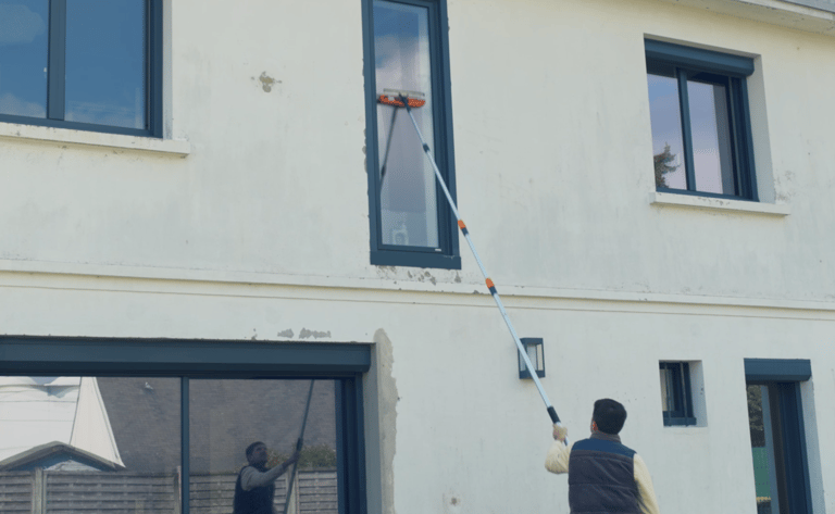 a man is cleaning a house with a window cleaner