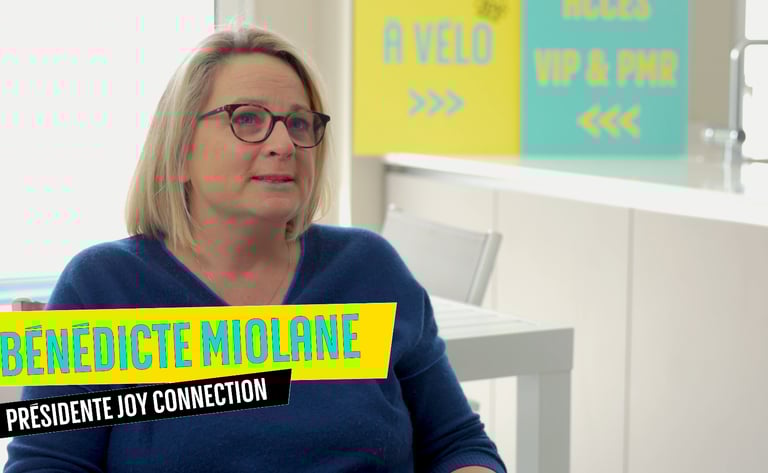 a woman in a blue sweater and glasses sitting at a desk