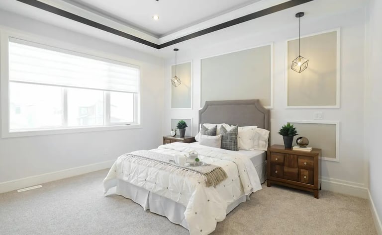 Modern master bedroom with a grey upholstered headboard, white bedding, and geometric pendant lights.