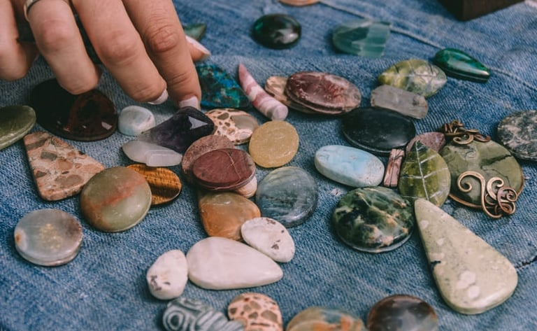 Seleccionando a mano cristales  y piedras semipreciosas sobre una tela de mezclilla azul.