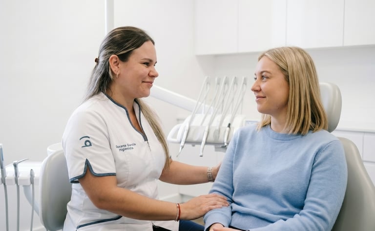 A friendly dental hygienist consulting with a patient in a modern dental office chair.