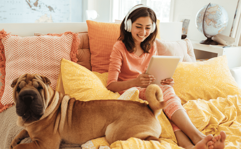 a woman sitting on a bed with a dog and a laptop
