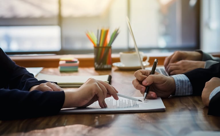 a group of people sitting at a table with papers and pens