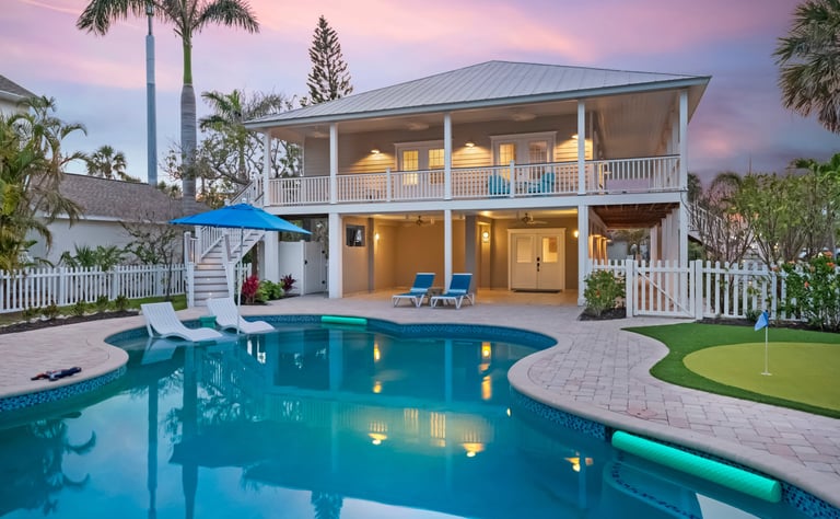 Luxury Florida vacation rental home with a private swimming pool, outdoor patio, and putting green at sunset.