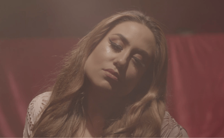 A person with their long brown hair and light brown skin with eyes closed and head tilted right.
