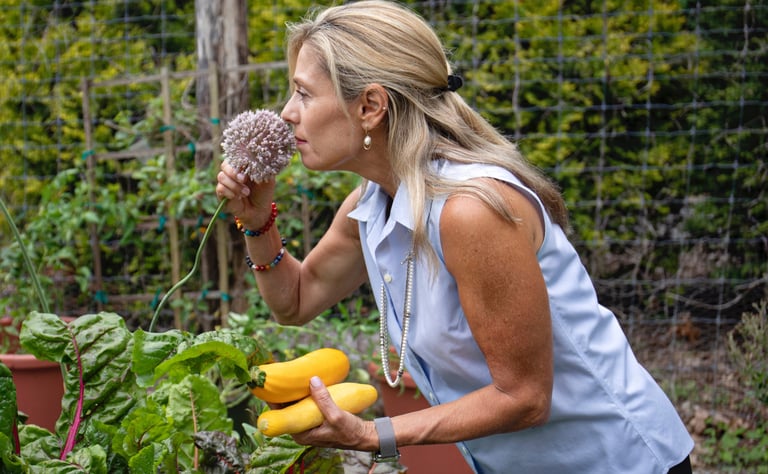 a woman in a blue shirt is holding a garlic chive blossom