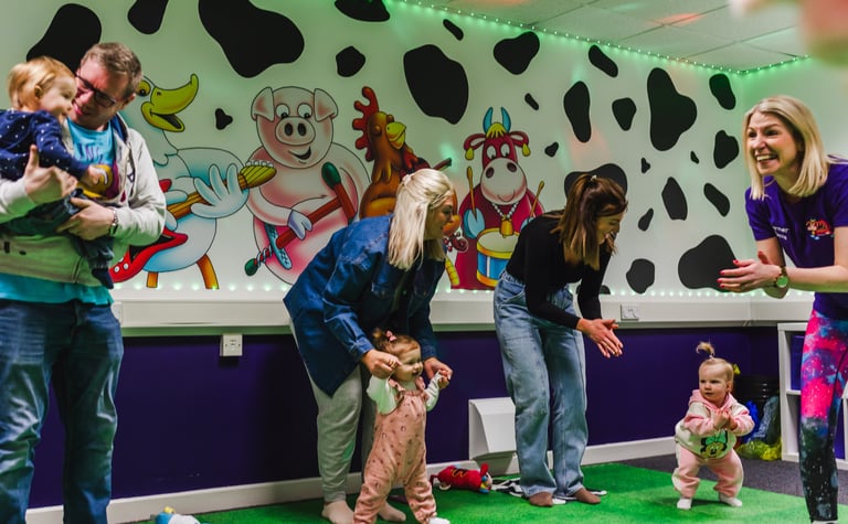 a group of parents, dancing with their children in moo music class.