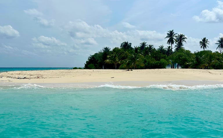 Pristine white sand beach with turquoise waters and swaying palm trees on Hulhudheli Island, Maldive