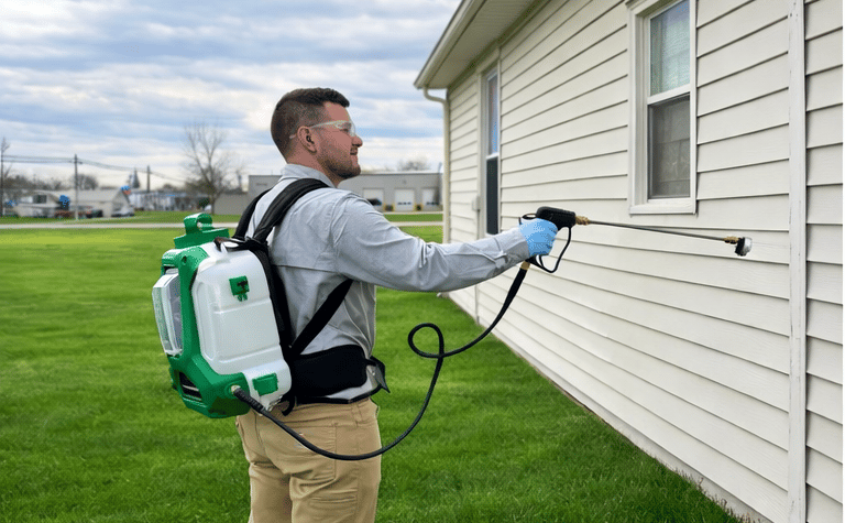 Pest control technician servicing house for spiders