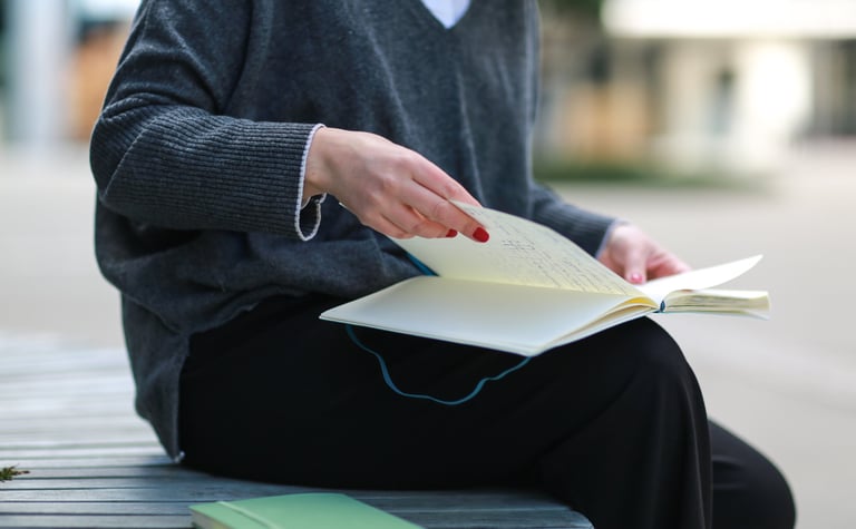 a woman sitting on a bench reading notes