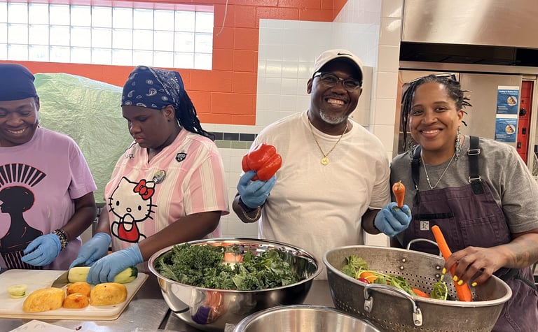 Smiling group of volunteers preparing healthy vegetables in a community kitchen.