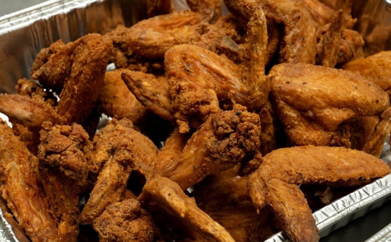 A silver tray filled with crispy, golden-brown deep-fried chicken wings.