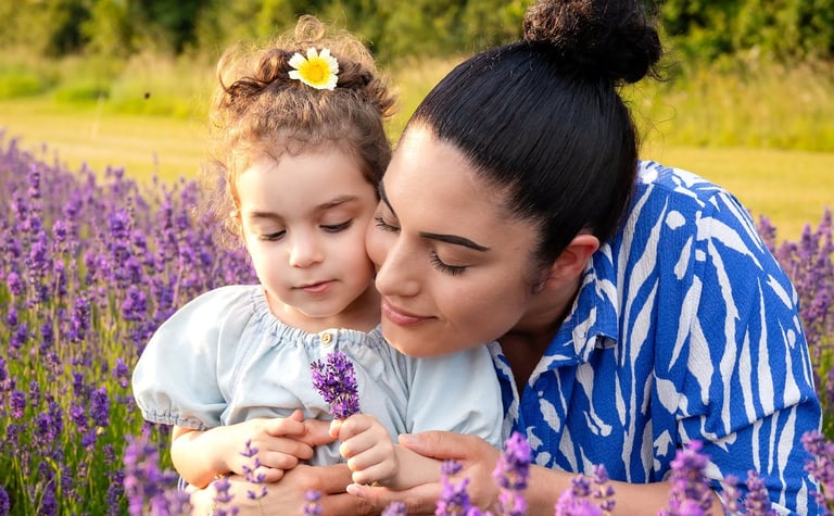 A mother and young daughter bonding in a blooming purple lavender field during golden hour.