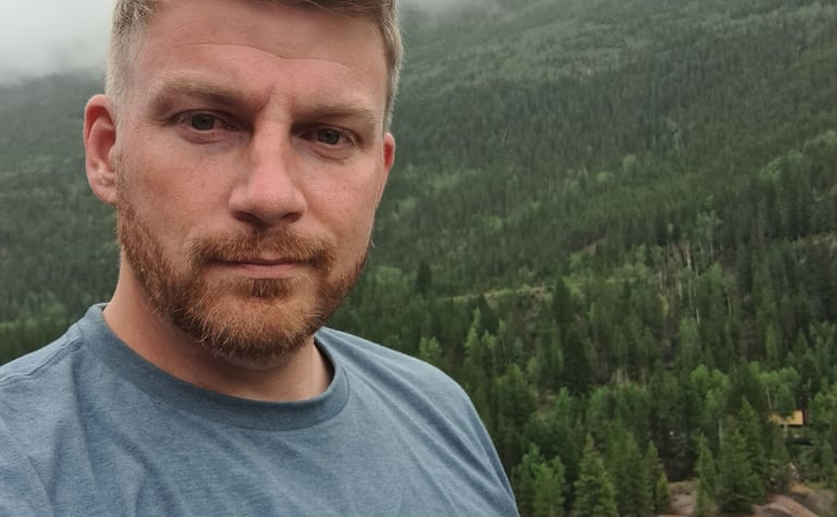 Daniel Ferguson at the top of a mountain peak in Colorado.