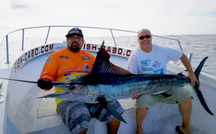 two men are holding a fish on a boat