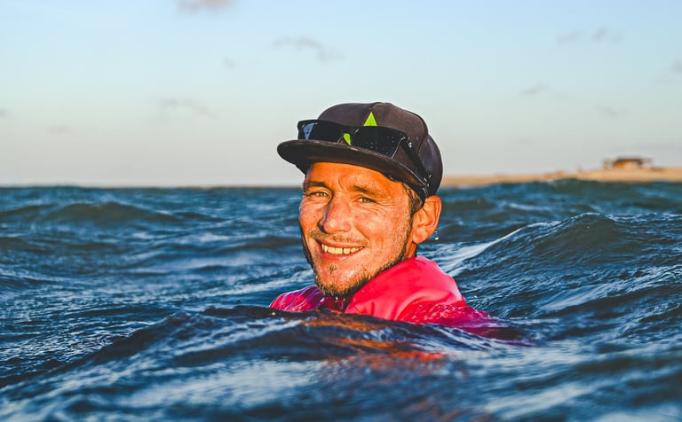 a man in a red shirt is smiling and holding a surfboard