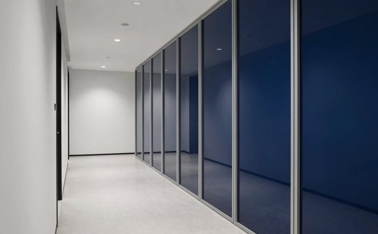 Wide shot of a modern, minimalist law firm corridor with mist white walls and midnight blue glass partitions, reflecting a sense of order and authority.