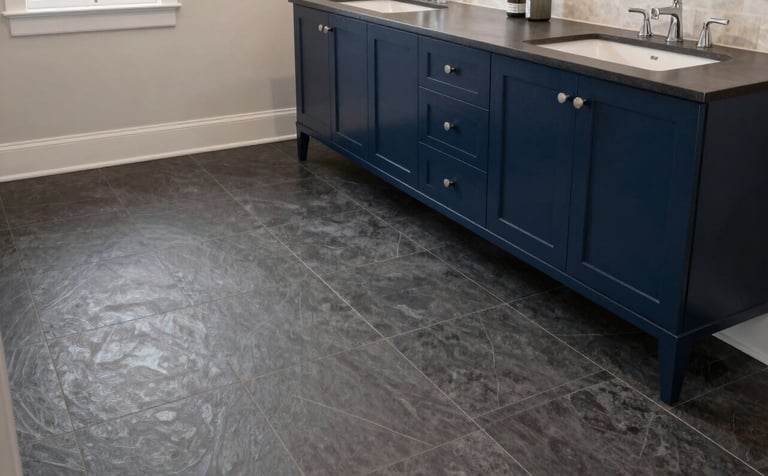 A wide-angle, premium shot of a finished luxury bathroom remodel in a North American / US home. The flooring consists of elegant charcoal dark gray tiles that complement the deep navy blue vanity. The lighting is soft and professional, highlighting the flawless installation and modern, clean aesthetic.