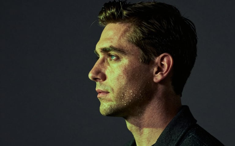 A visually powerful studio portrait of a modern professional. Dramatic lighting with vibrant lime green accents hitting the subject's profile against a deep charcoal backdrop. Impactful and credible aesthetic.