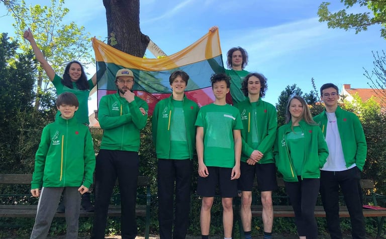 a group of people standing in front of a bench holding Lithuanian flag