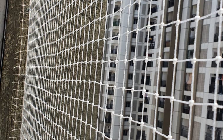 Installation of bird protection nets across a residential building duct area. Professional workers i