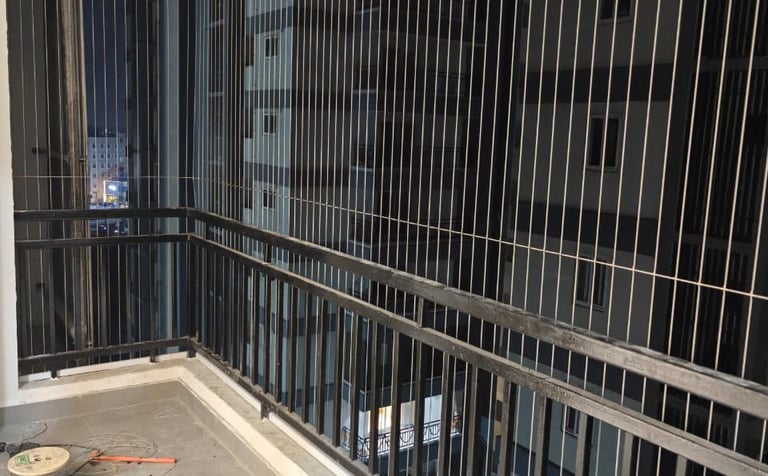 A luxury apartment balcony featuring modern invisible grills made of thin stainless steel cables. Th