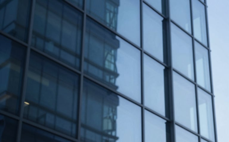 Abstract and sophisticated composition of blue architectural glass reflecting light. The image represents stability, structure, and professional transparency. Shades of #0A1C29 and #2E5C6E dominate the reflection, creating a trustworthy brand visual.