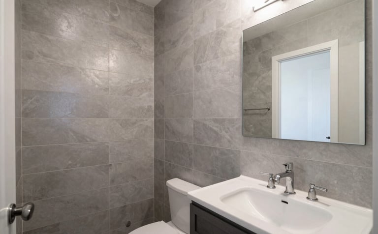 A stunning, modern bathroom remodel in a New Mexican residence. Features elegant silver-gray tiles, professional plumbing fixtures, and clean architectural lines. Soft, bright natural lighting.