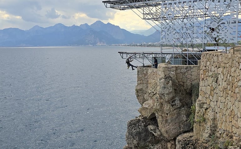 a man standing on a cliff face down into the ocean