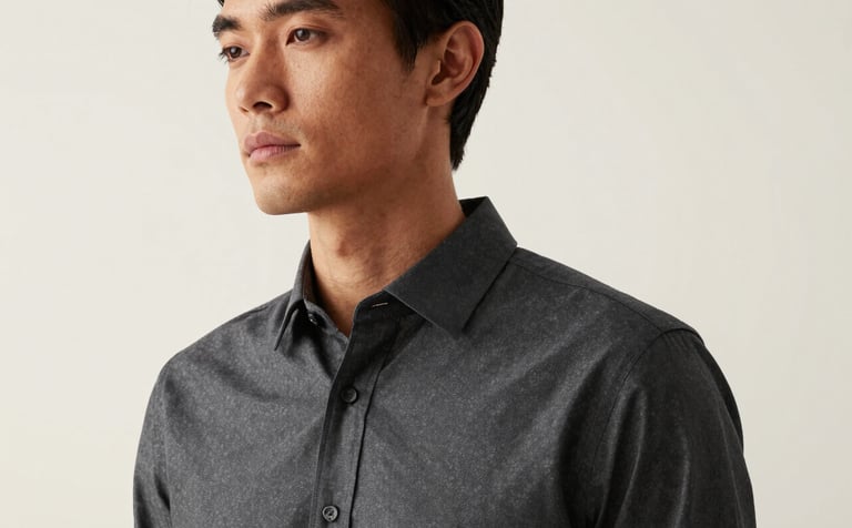 A minimalist professional portrait of a person against a creamy white background, soft natural side-lighting, wearing a smart charcoal shirt, sophisticated and approachable look.