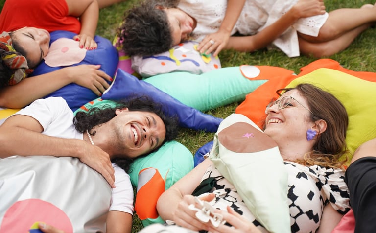 Quatre personnes allongées sur des sculptures souples de parties du corps.