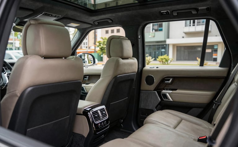 Interior of a luxury SUV, showing spacious leather seats and high-tech amenities. Soft natural lighting entering through tinted windows. Modern and clean aesthetic. South American / Brazilian context visible in the urban background through the glass.
