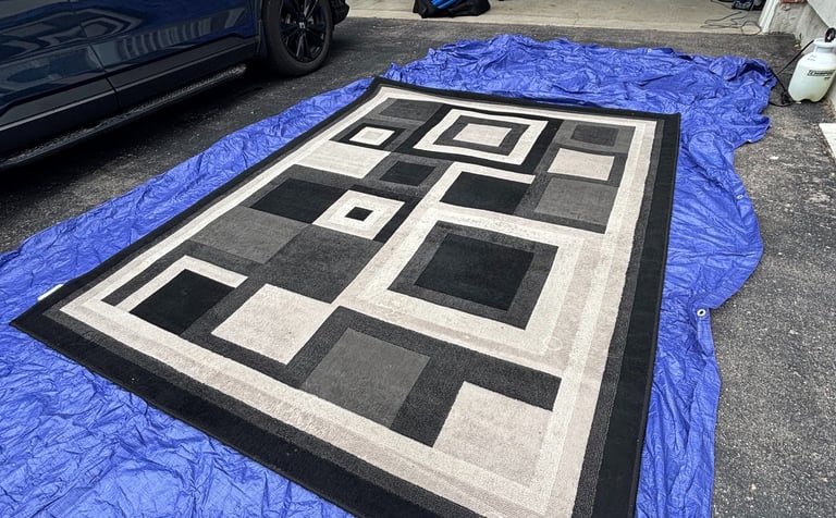 Black and white rug being professionally cleaned on an external work area.