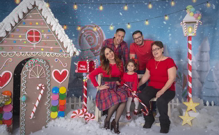 a family posing for a photo in front of a gingerbread house