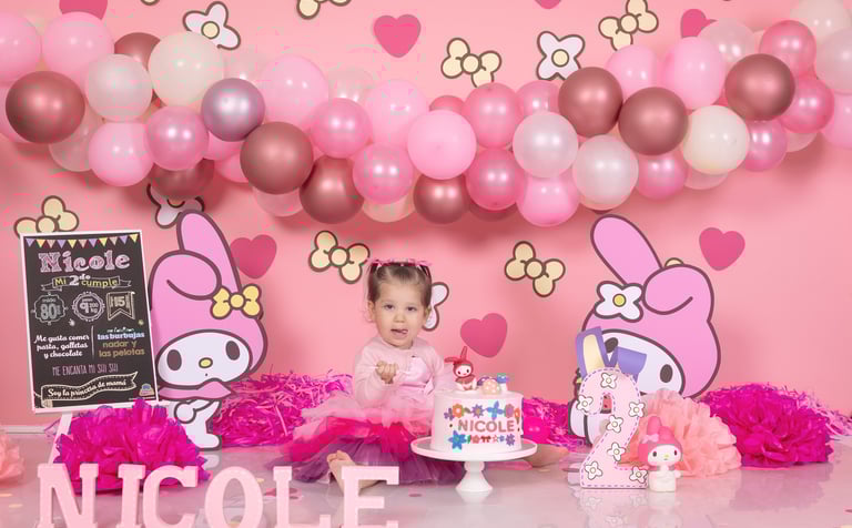a baby girl in a pink dress and pink balloons