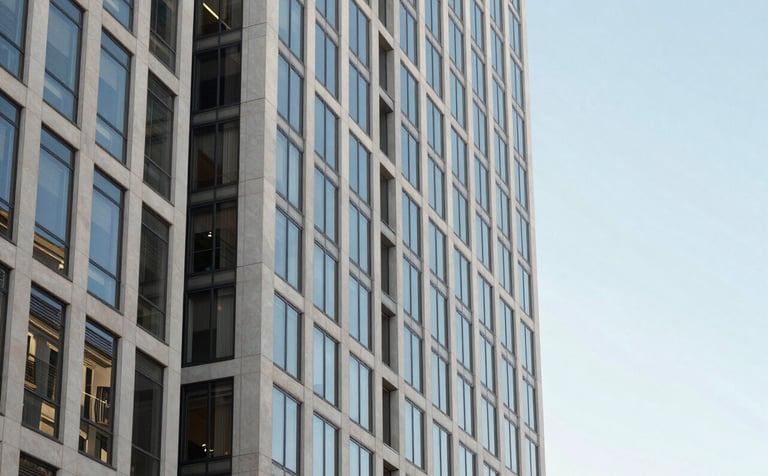 Architectural photography of a contemporary financial district in the North American West Coast. A sharp focus on a glass and steel building reflecting a clear morning sky. The image uses a clean palette of off-white and light blue, conveying stability.