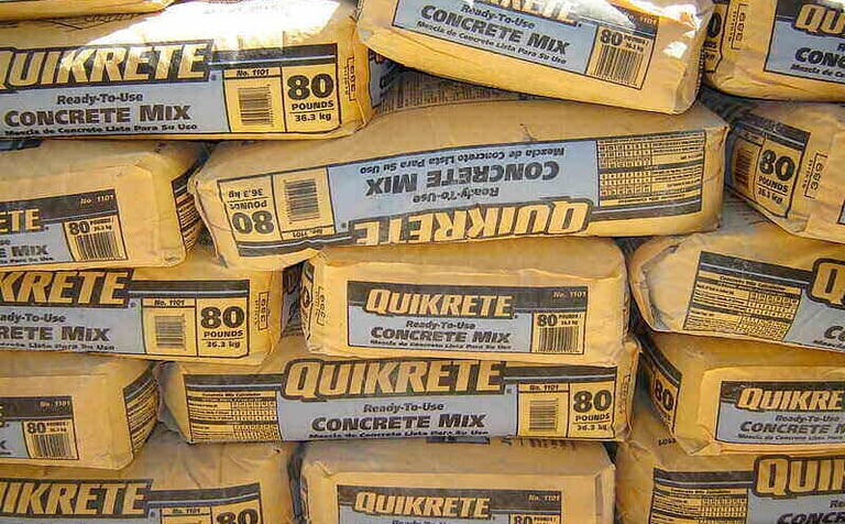 Stacked 80-pound bags of Quikrete ready-to-use concrete mix for construction projects.