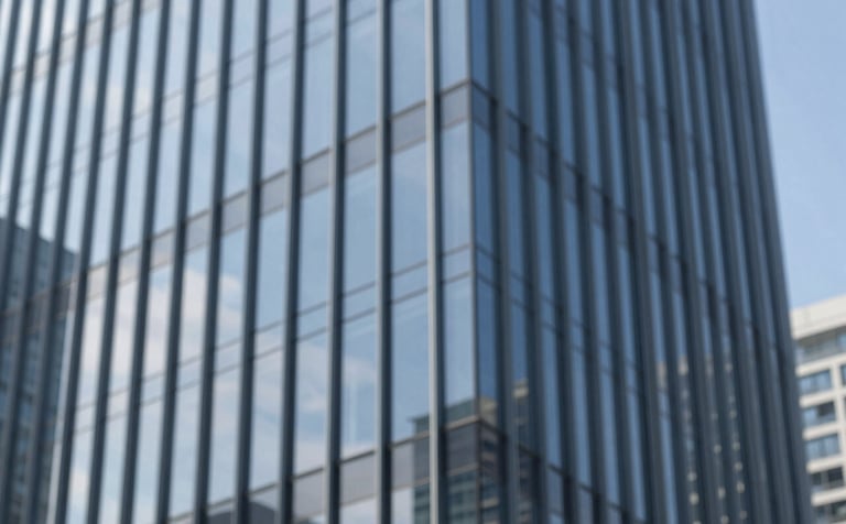 External view of a modern corporate building with a sleek glass curtain wall facade. The glass reflects a clear blue sky, emphasizing innovation and precision. The aesthetic is sharp and professional, utilizing brand tones #1A1D20 and #5B6C7B.