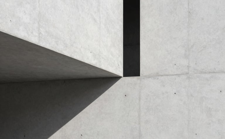 A minimalist architectural detail showing sharp shadows on a smooth light grey concrete wall. North American / International studio aesthetic with high-contrast, editorial lighting and precise lines.
