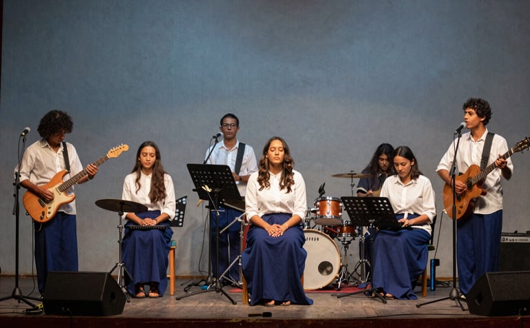 Photography of a modern music team with instruments on a stage in a Central American / Costa Rican sanctuary, warm atmospheric lighting, muted steel blue backdrop, ghost white and deep navy blue tones, spiritual and inviting mood.