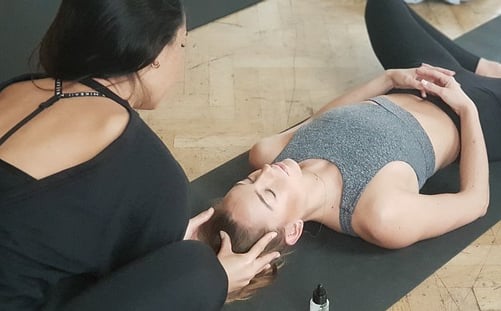 Yogalehrerin begleitet Schülerin in Savasana – persönliche Einzelstunde mit achtsamer Berührung