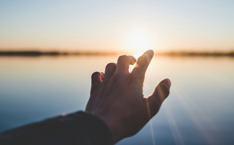 Hand reaching toward sunrise symbolizing hope and new beginnings after probate