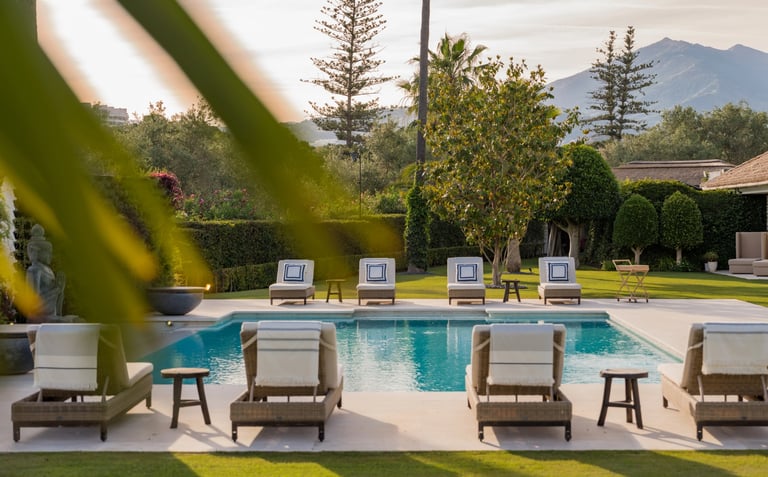Sun loungers and palm garden by the pool at Villa El Olivo, Marbella