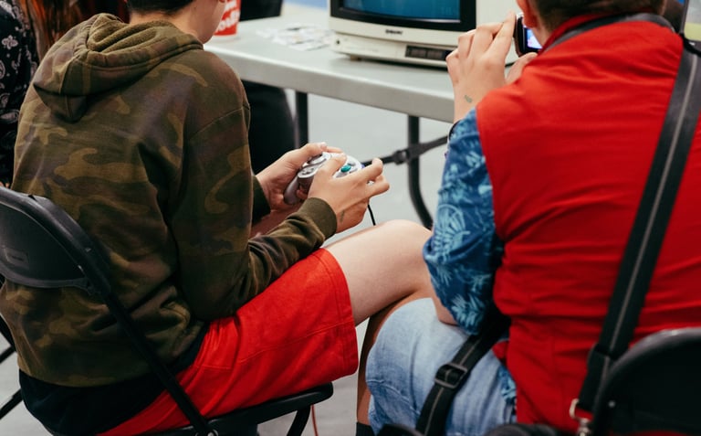 Close up image of two people sitting at an old tv playing some video games together at the event.