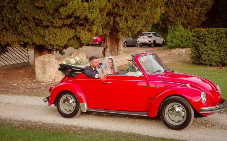 Sposi che arrivano sorridenti a bordo del nostro maggiolone rosso, nella location del ricevimento.